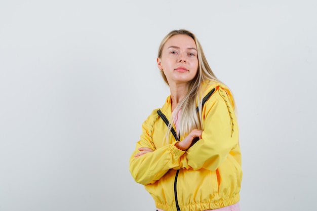 Señorita de pie con los brazos cruzados en camiseta, chaqueta y mirando confiado