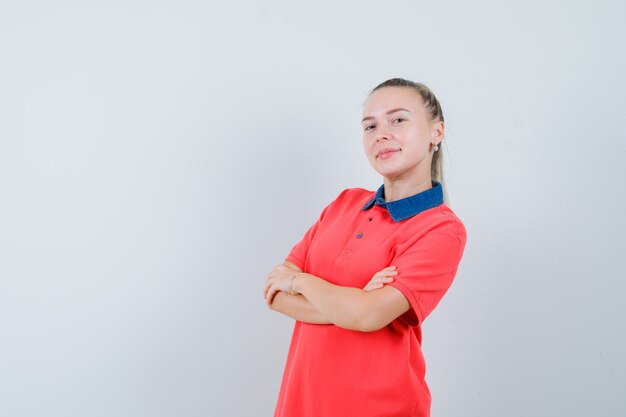 Señorita de pie con los brazos cruzados en camiseta y mirando confiado