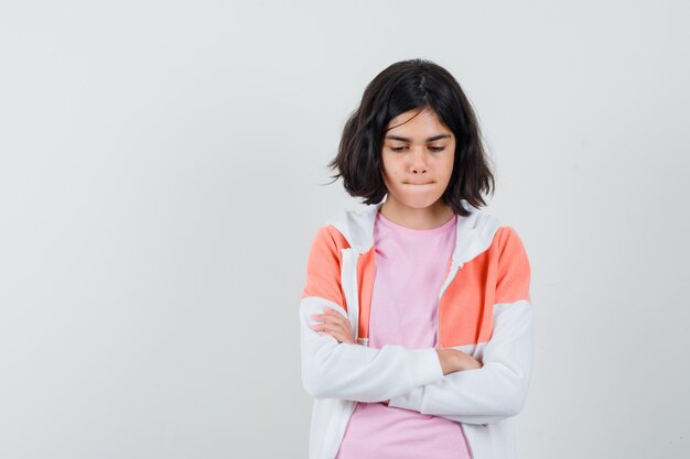 Señorita de pie con los brazos cruzados en la chaqueta, camisa rosa y mirando molesto