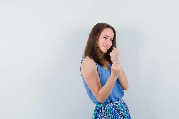 Señorita de pie en una pose de boxeador en camiseta, falda y mirando alegre