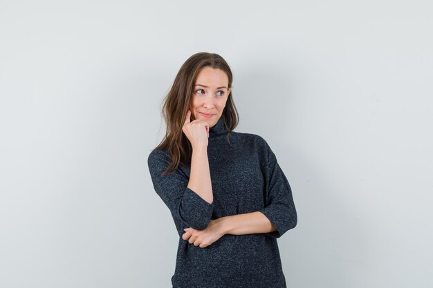 Foto gratuita señorita de pie en pose de pensamiento en camisa y mirando alegre