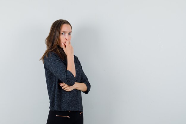 Señorita de pie en pose de pensamiento en camisa