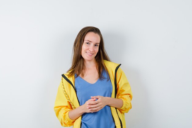 Señorita de pie en pose de pensamiento en camiseta y mirando confiado, vista frontal.