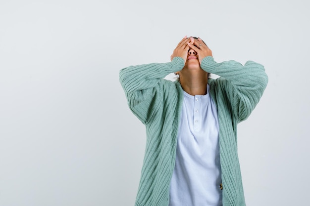 Señorita que cubre la cara con las manos en camiseta, chaqueta y con aspecto cansado