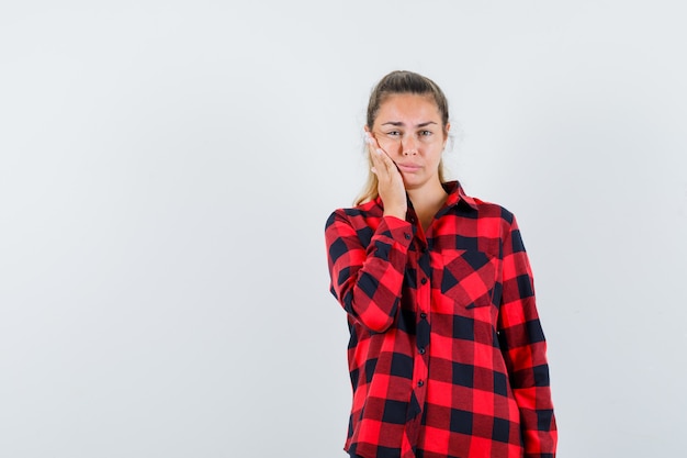 Señorita que sufre de dolor de muelas en camisa a cuadros y parece incómodo