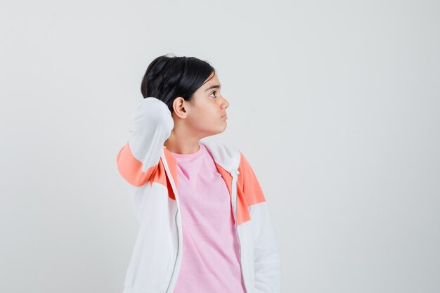 Señorita recogiendo su cabello mientras mira a un lado en chaqueta, camisa rosa.