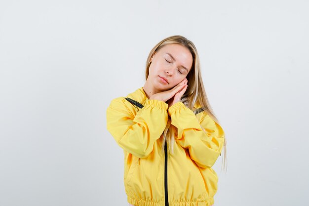 Señorita recostada mejilla en las manos en camiseta, chaqueta y aspecto soñoliento