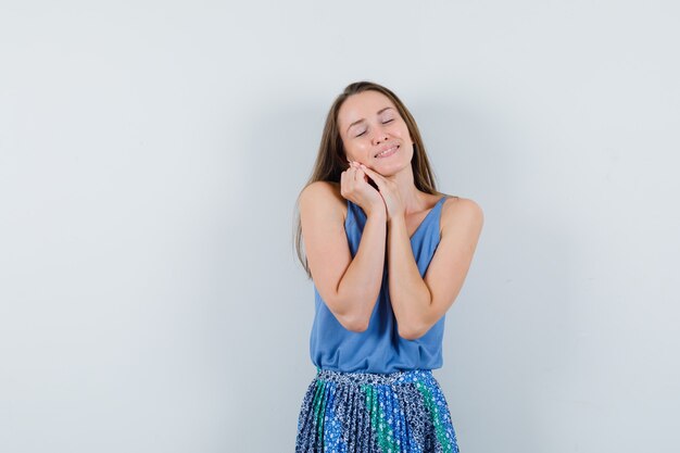 Señorita recostada mejilla en manos entrelazadas en camiseta, falda y aspecto elegante