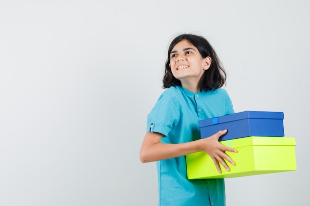 Señorita sosteniendo cajas de regalo de colores en camisa azul y mirando contenta.