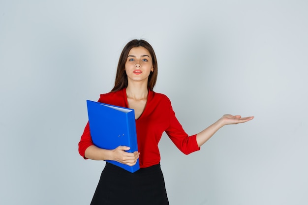 Señorita sosteniendo la carpeta mientras muestra algo en blusa roja