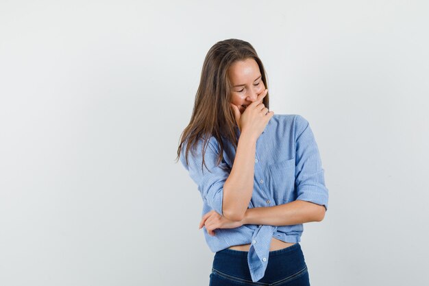 Señorita sosteniendo la mano en la boca mientras se ríe con camisa azul