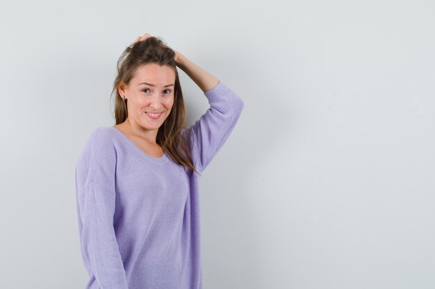 Señorita sosteniendo la mano en la cabeza en camisa casual y luciendo bonita