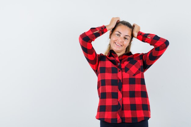 Señorita tomados de la mano en la cabeza con camisa a cuadros y aspecto encantador