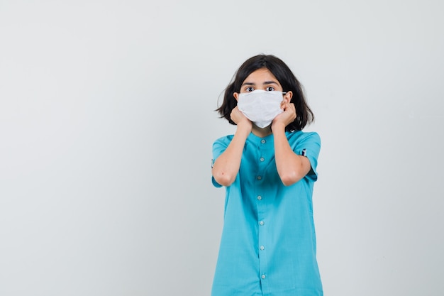 Señorita vistiendo una mascarilla blanca con camisa azul y mirando listo