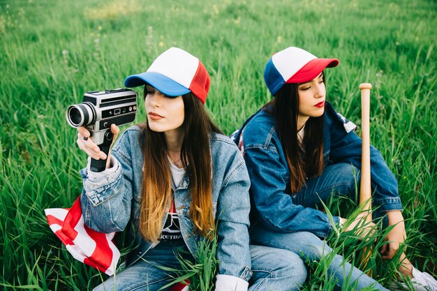 Señoritas, sentado en la hierba verde con gorras de colores