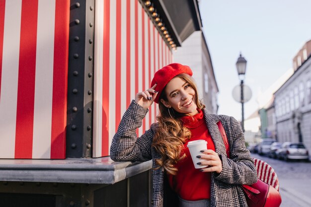 Sensual chica francesa con manicura negra disfrutando de una sesión de fotos en la avenida en la mañana de otoño