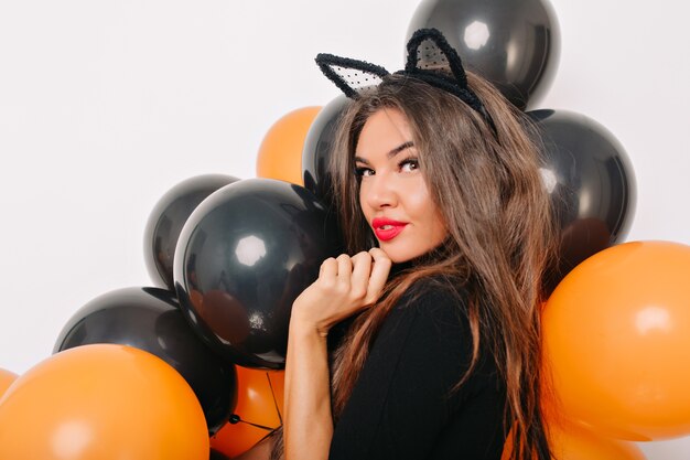 Sensual mujer bronceada posando con globos de halloween