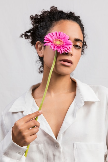 Foto gratuita sensual mujer con flor cubriendo ojo.