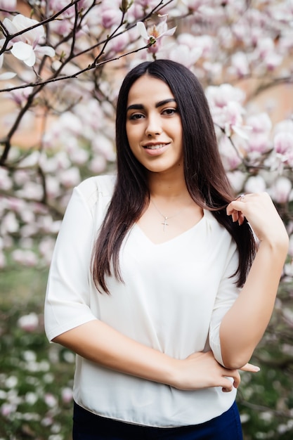 Sensual mujer joven primavera en árbol floreciente de magnolia