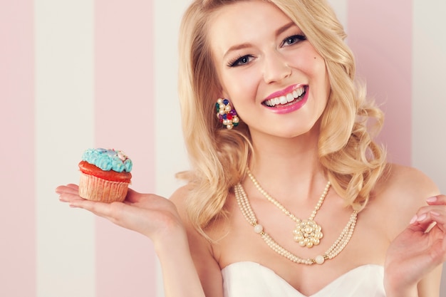 Sensual mujer sonriente posando con muffin azul