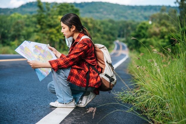 Foto gratuita sentado y mirando el mapa en el camino.