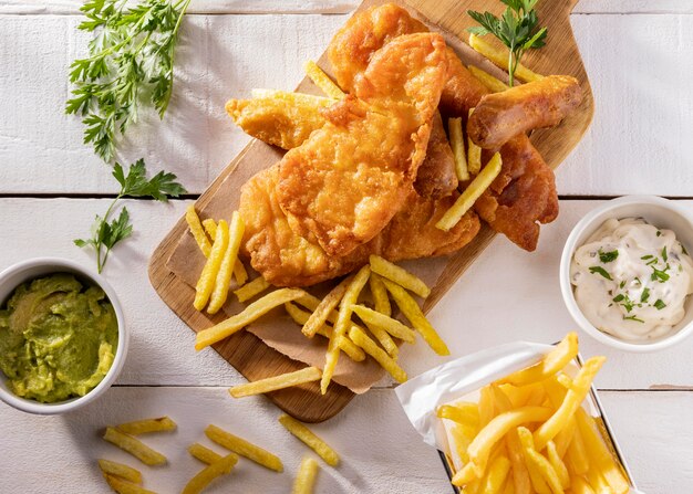 Sentar planas de pescado y patatas fritas sobre una tabla de cortar con salsa