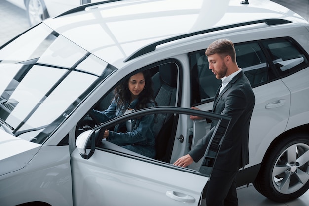 Foto gratuita sentirás comodidad. clienta y empresario barbudo con estilo moderno en el salón del automóvil