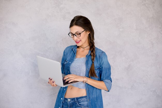 Sentirse bien mujer con anteojos de pie enfocado a la computadora portátil