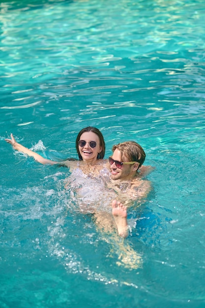 Sentirse bien. Una pareja joven nadando en una piscina y sintiéndose emocionada