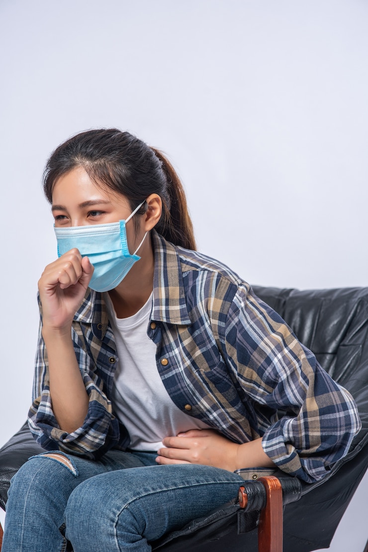 Photo Gratis seorang wanita yang tidak nyaman duduk di kursi dan mengenakan masker