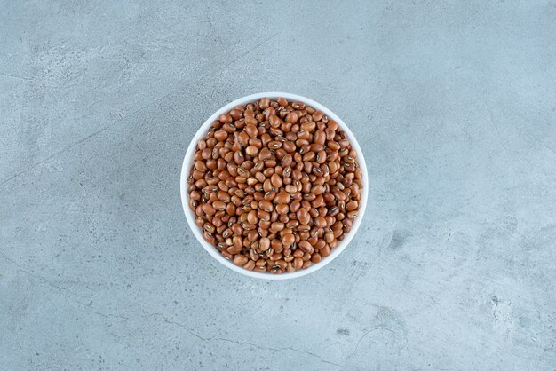 Seque los frijoles marrones en una taza de cerámica blanca. Foto de alta calidad