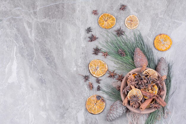 Seque las rodajas de naranja, las ramas de canela y las flores de anís en una taza de madera