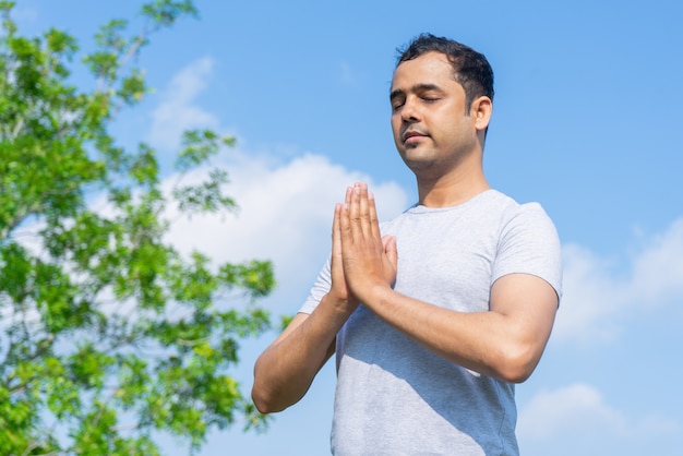 Foto gratuita sereno joven indio meditando al aire libre con los ojos cerrados