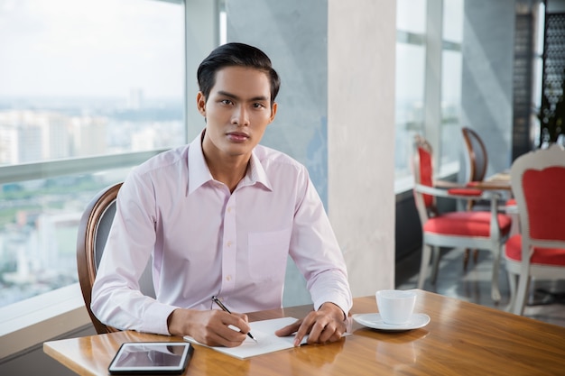 Seria asiática Escritura del hombre joven en café