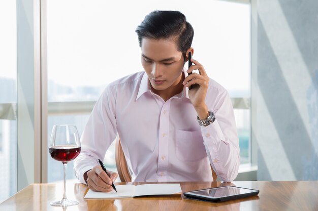 Seria joven asiática hombre en café que invita al teléfono