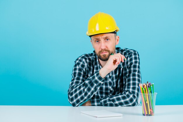 En serio, el arquitecto está mirando a la cámara sentado en el fondo azul