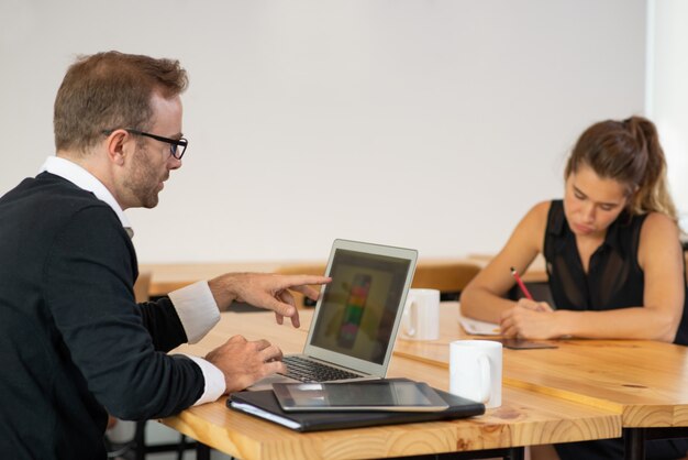 Foto gratuita serio hombre de negocios y la mujer que trabaja en los escritorios.