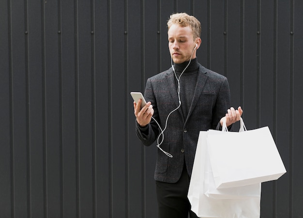 En serio hombre de negro con auriculares y teléfono inteligente