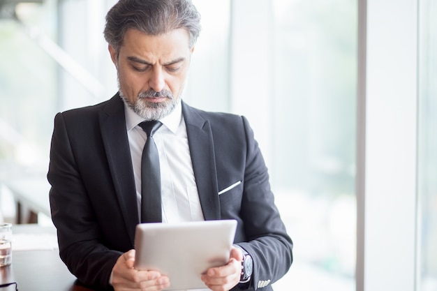 Serio líder de negocios de mediana edad utilizando tableta