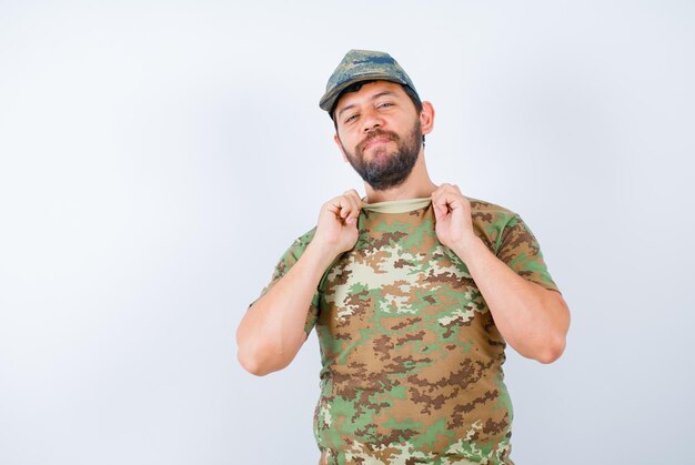 En serio, el soldado está mirando a la cámara sosteniendo su cuello de camisa sobre fondo blanco.