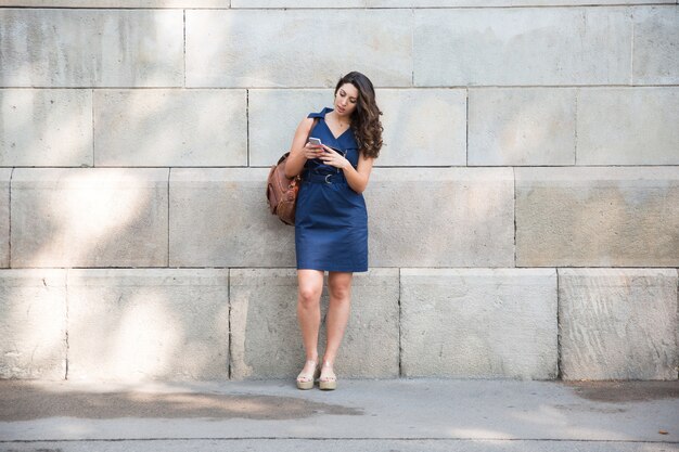 Serio viajero femenino utilizando teléfono móvil al aire libre