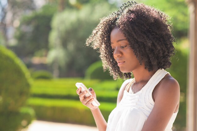 Serious Black Lady Texting en el teléfono inteligente en el Parque