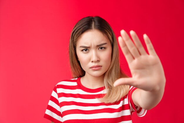 Seriouslooking alarmado enojado mujer asiática tirar de la mano hacia adelante no detener ninguna señal exigiendo y prohibiendo ser ...