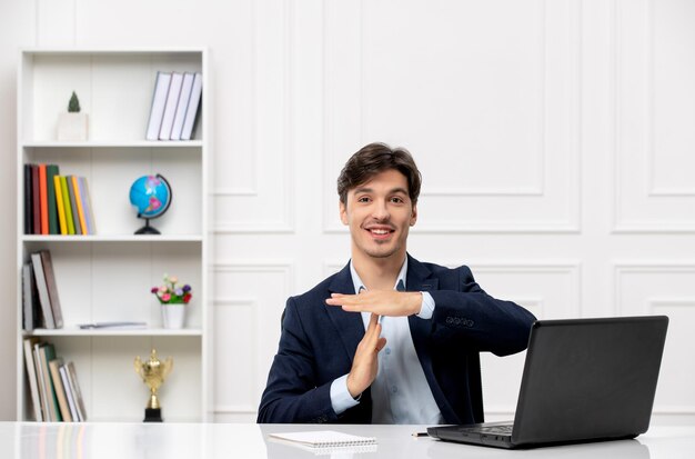 Servicio al cliente, el lindo chico moreno en el traje con una computadora portátil que muestra la señal de stop