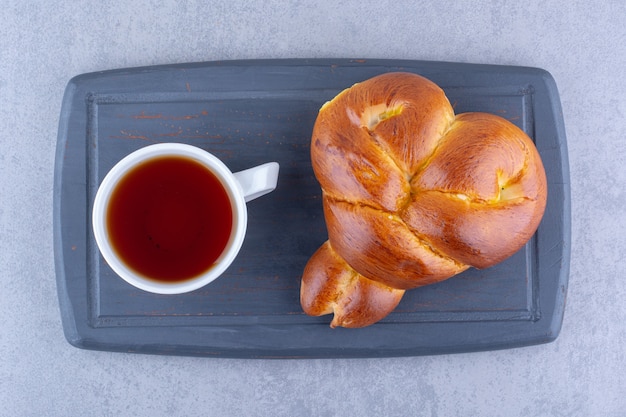 Servicio de desayuno de té y bollo dulce en una placa sobre superficie de mármol