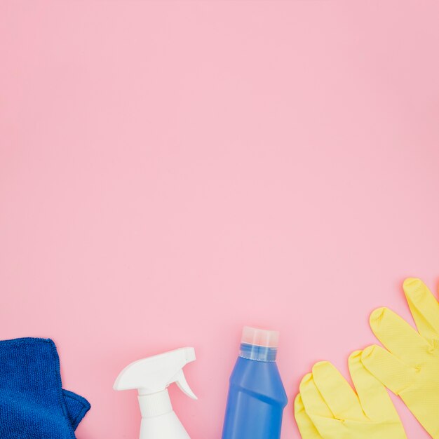 Servilleta azul Botella de detergente y spray sobre fondo rosa