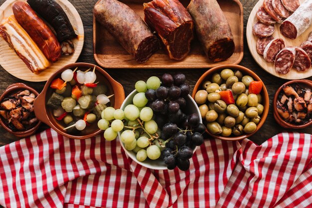 Servilleta y uvas cerca de encurtidos y salchichas