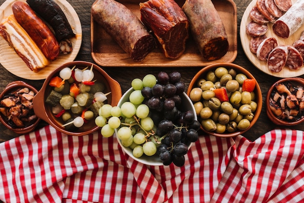 Servilleta y uvas cerca de encurtidos y salchichas