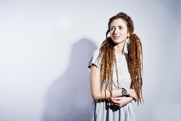 Sesión de estudio de chica en vestido gris con rastas sobre fondo blanco.