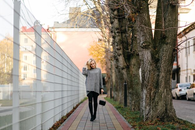 Sesión de fotos de la calle de la moda de elegante joven en una ropa gris